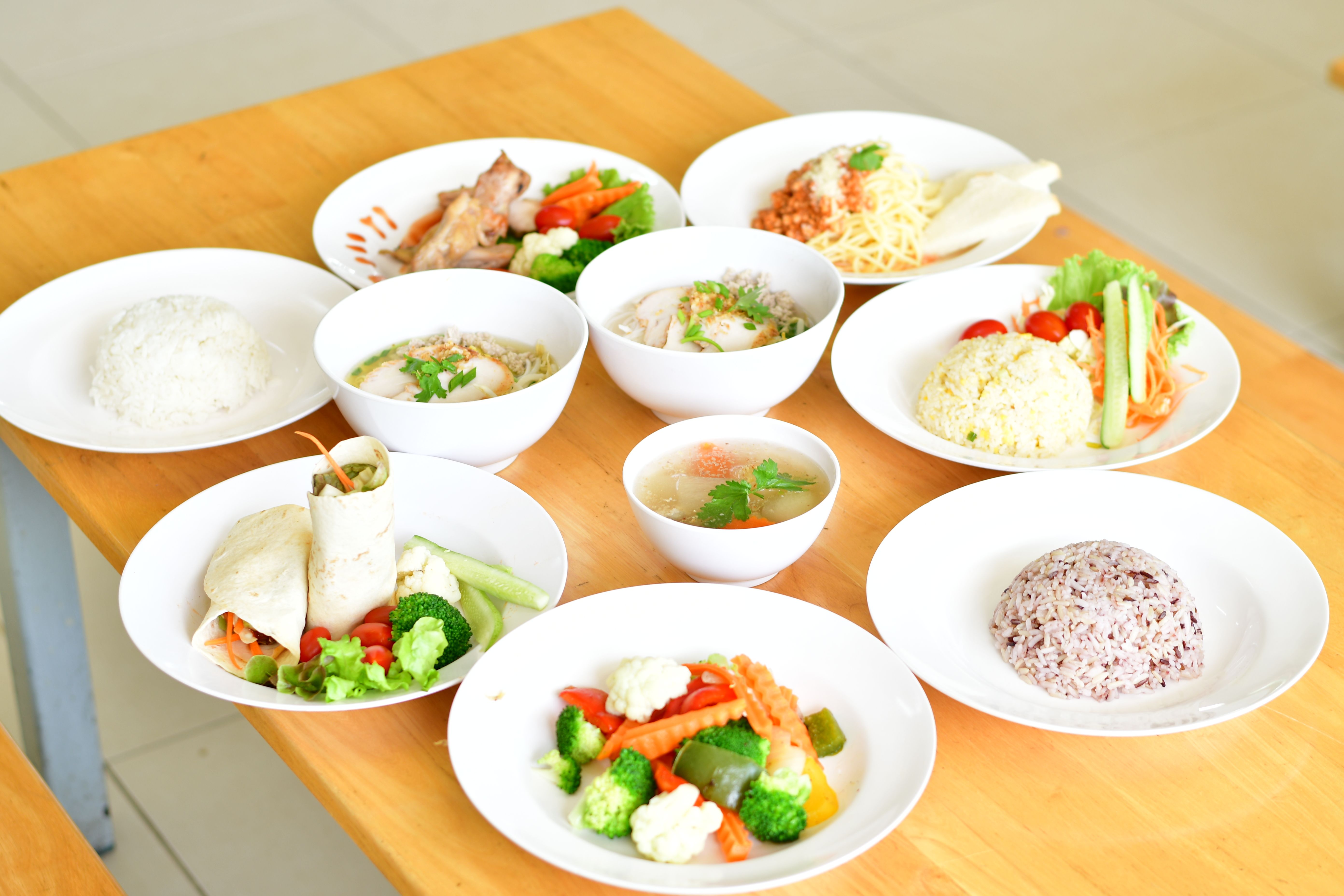 木のテーブルに並ぶ、ご飯・スープ・野菜・雑穀米などバランスの良い食事