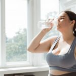 運動後に水分補給をする女性(涼しい室内でのトレーニングのイメージ)
