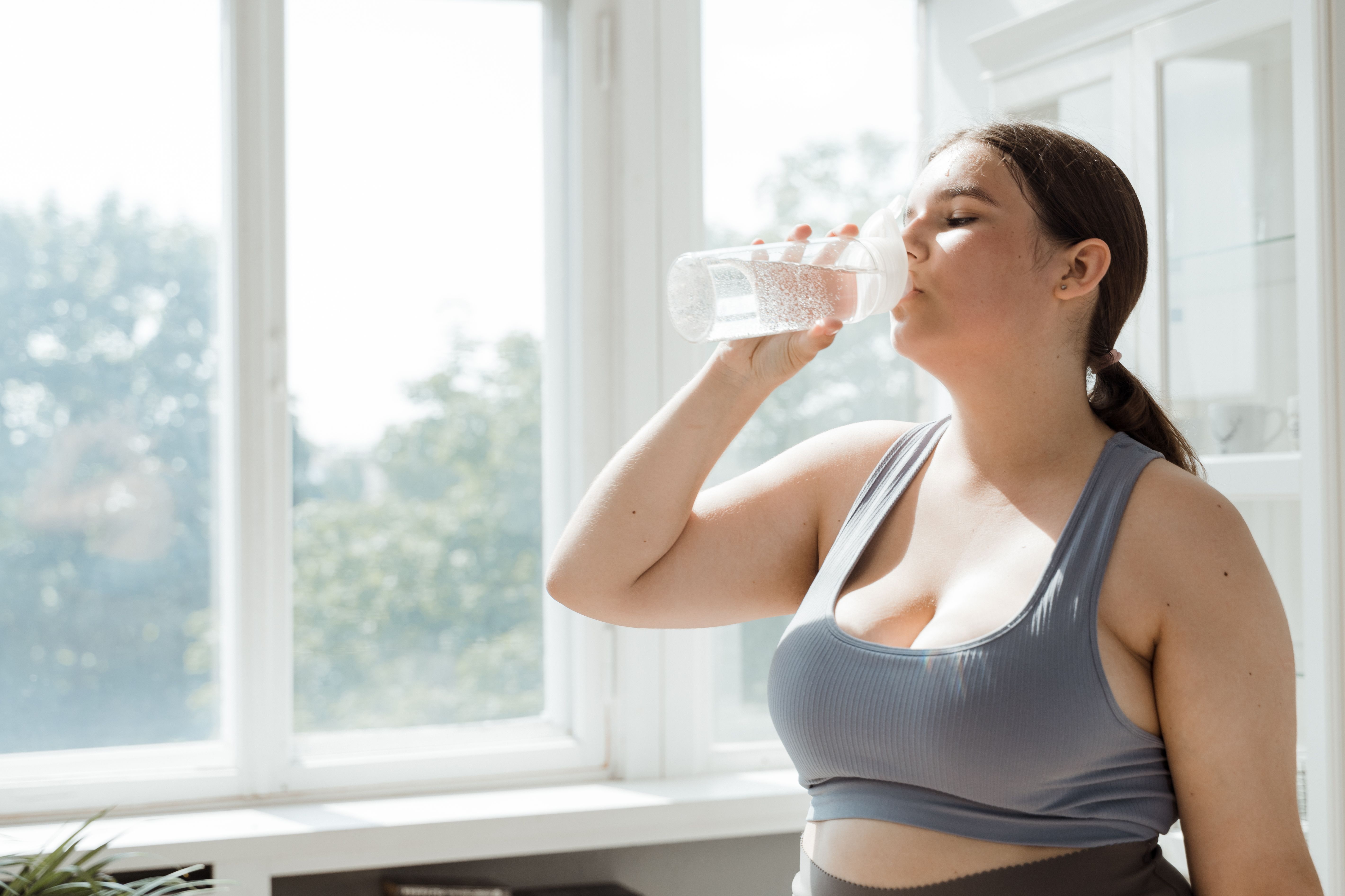 運動後に水分補給をする女性（涼しい室内でのトレーニングのイメージ）