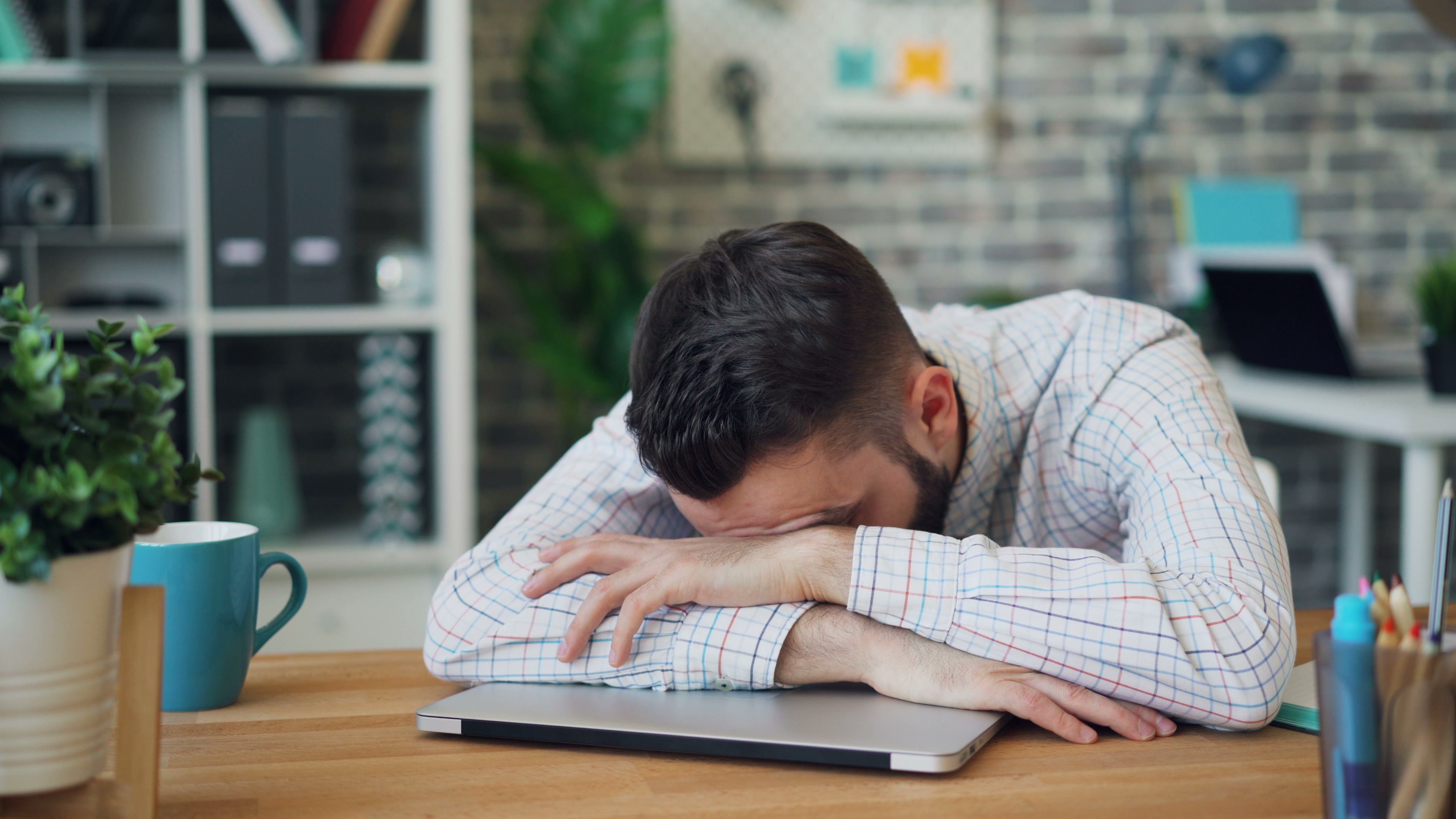 昼食後にオフィスの机で強い眠気とだるさを感じる会社員
