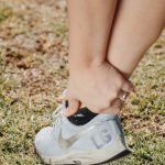 スニーカーを履いた足首とかかとを手で押さえている様子