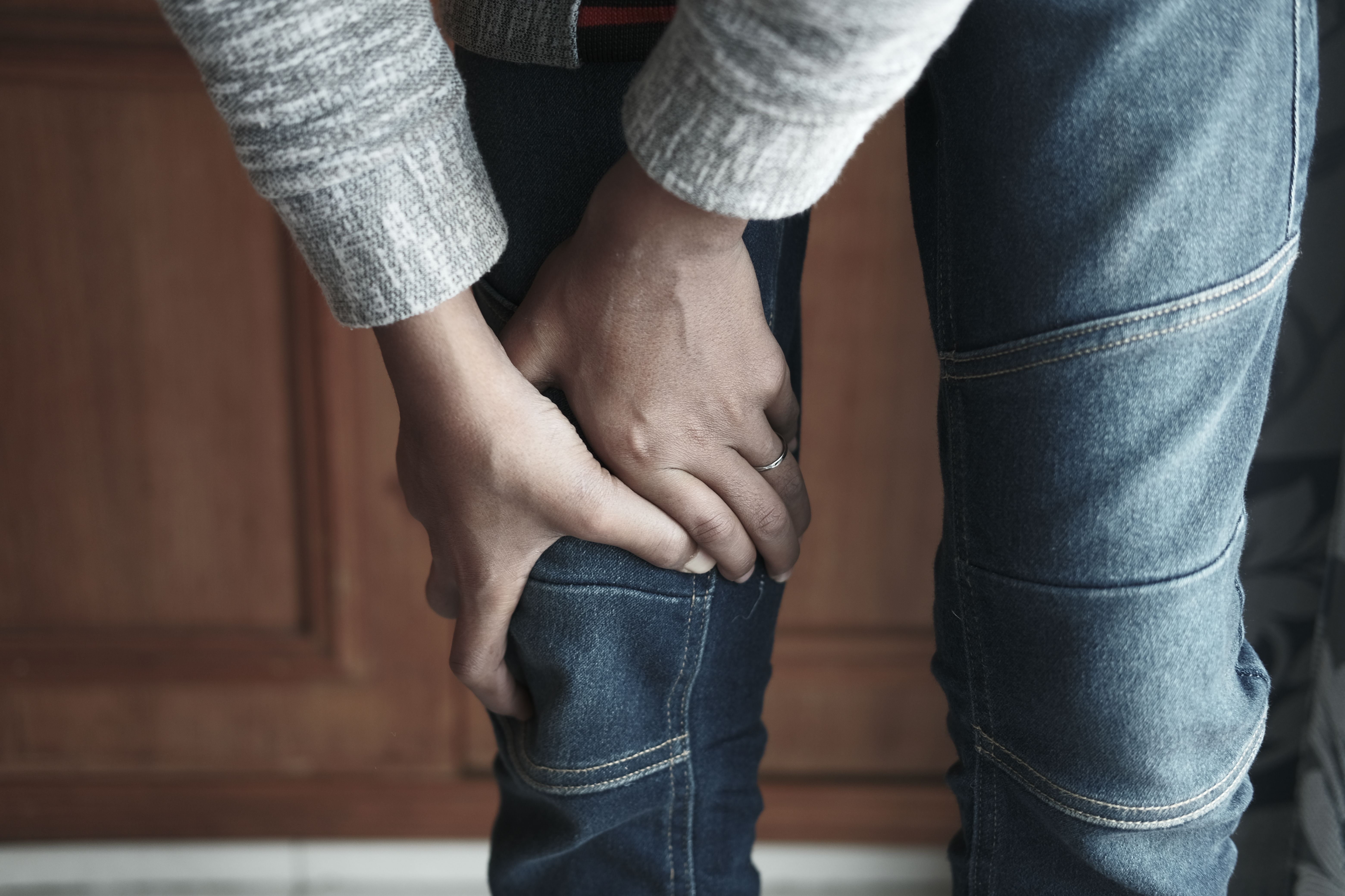 膝を両手で押さえる人。階段を降りるときの膝の違和感