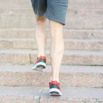 階段を上る人の脚元。階段の上り下りは膝への負担が大きい