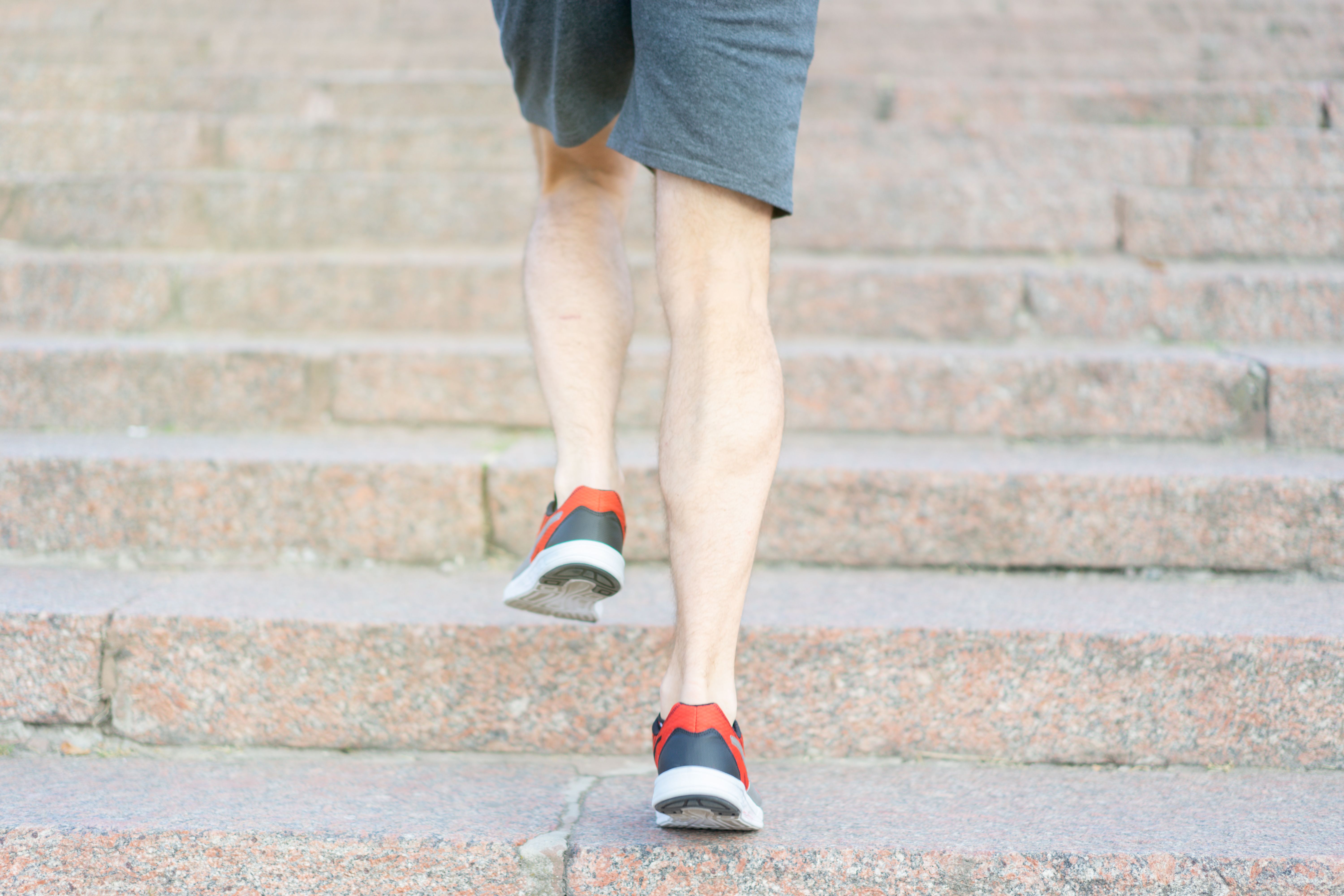 階段を上る人の脚元。階段の上り下りは膝への負担が大きい