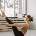 明るいスタジオで体幹を使ったピラティスのポーズをとる女性