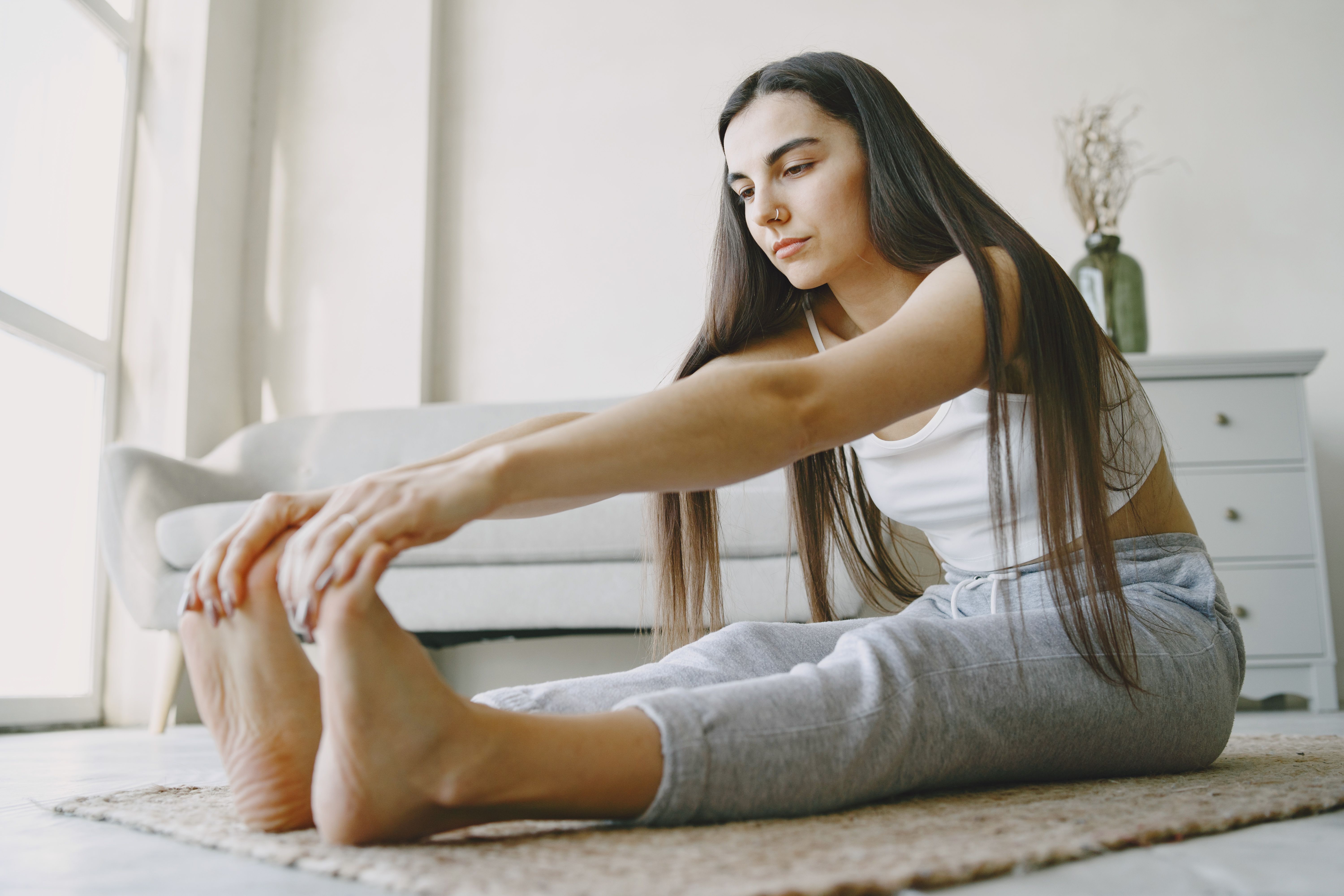 明るい部屋で背中を伸ばすストレッチをする女性（セルフケアのイメージ）