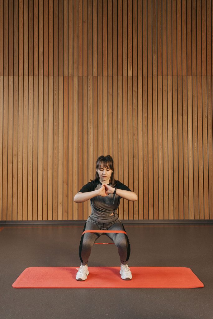 ゴムバンドを脚に巻いてスクワットをする女性