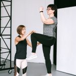 明るいスタジオでトレーナーと一緒に運動する40代女性