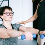 パーソナルトレーナーの指導でダンベルを使ったトレーニングを行う女性